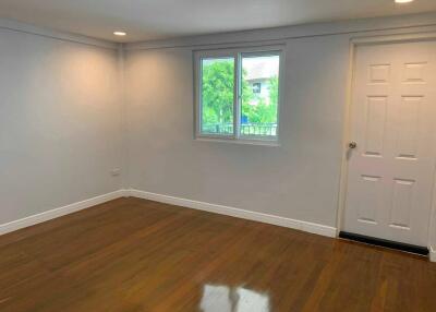 Spacious empty bedroom with wooden floors and a window