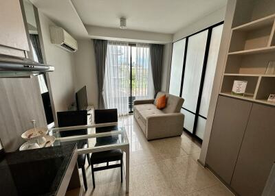 Comfortable living room with a kitchenette, glass dining table, and sliding door to the balcony