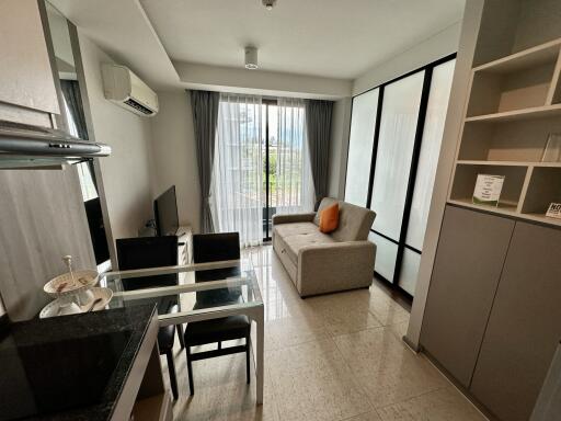 Comfortable living room with a kitchenette, glass dining table, and sliding door to the balcony