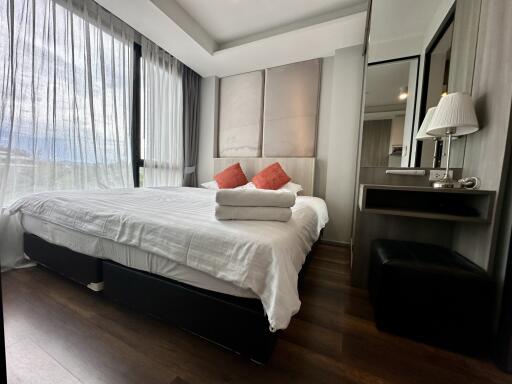 A modern bedroom with a large bed, nightstand, and floor-to-ceiling windows