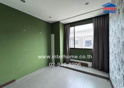 Empty bedroom with green and white walls, large window, and tiled floor