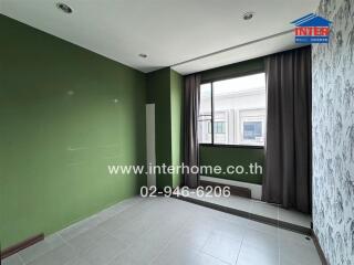 Empty bedroom with green and white walls, large window, and tiled floor