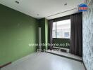 Empty bedroom with green and white walls, large window, and tiled floor