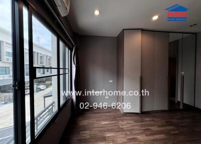 Bedroom with large window and wooden flooring