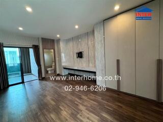 Spacious living room with wooden floor, built-in cabinets, and access to a balcony.