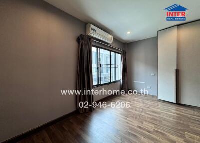 Spacious bedroom with large window, air conditioning, and wood flooring