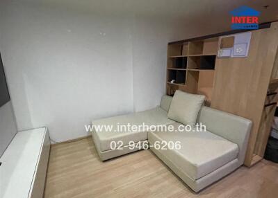 Compact living room with beige sofa and wooden shelving unit