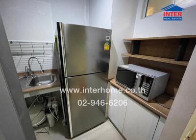 Compact kitchen with stainless steel refrigerator and microwave