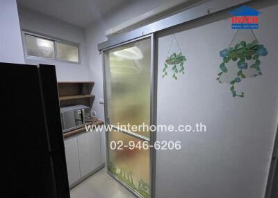 Small kitchen area with frosted sliding door, microwave, and shelves