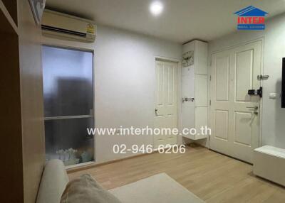 Living area with a hardwood floor, air conditioning, frosted glass window, white door, and beige sofa.