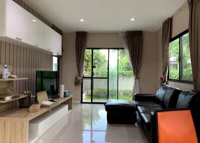 Modern living room with large windows, black leather sofa, and entertainment unit