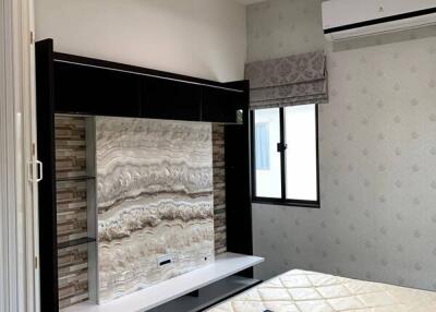 Modern bedroom with a wall-mounted TV, patterned wallpaper, and an air conditioning unit