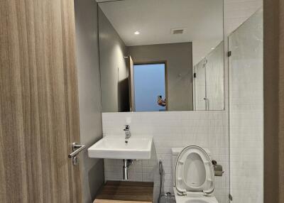 Modern bathroom with a large mirror, sink, and toilet