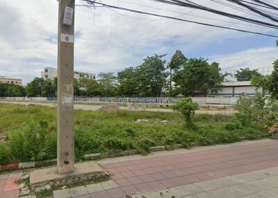 Vacant land view with surrounding trees and nearby buildings