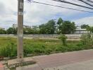 Vacant land view with surrounding trees and nearby buildings