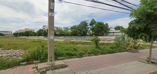 Vacant land view with surrounding trees and nearby buildings