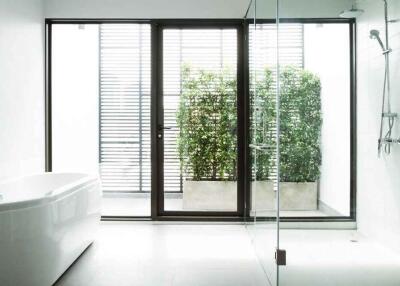 Modern bathroom with large bathtub, glass shower, and outdoor view