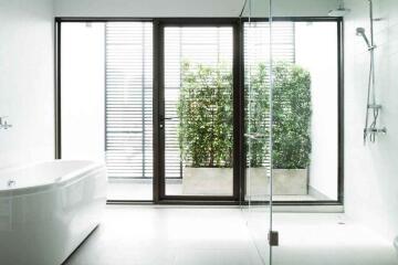 Modern bathroom with large bathtub, glass shower, and outdoor view