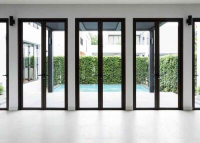 Modern living area with large glass doors opening to a courtyard with greenery