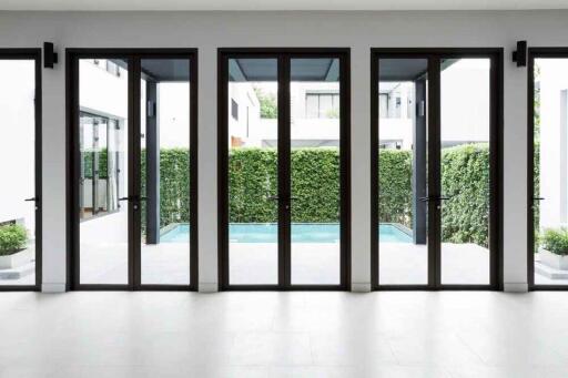 Modern living area with large glass doors opening to a courtyard with greenery