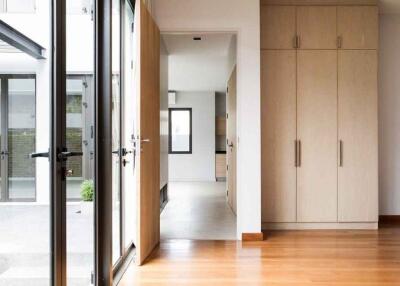 View of a modern hallway with large windows, a wooden floor, and built-in wooden cabinetry