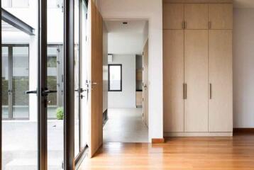 View of a modern hallway with large windows, a wooden floor, and built-in wooden cabinetry