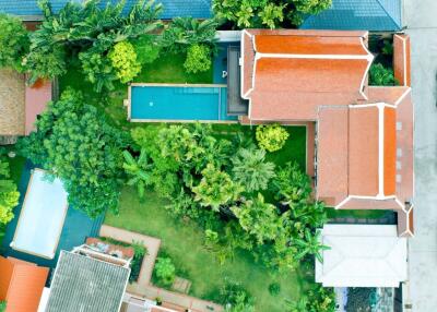 Aerial view of a property with a large house, swimming pool, and surrounding garden