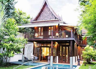 Exterior view of a large traditional wooden house with a pool