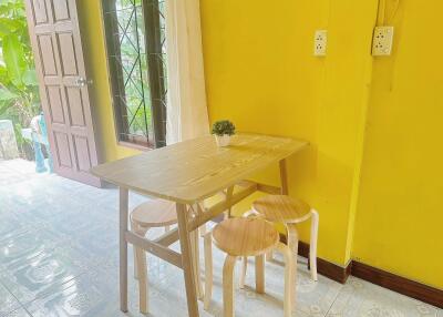 Small dining area with yellow walls, wooden table, and stools