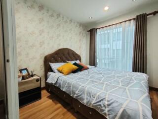 Bedroom with a double bed, patterned wallpaper, and a window with curtains