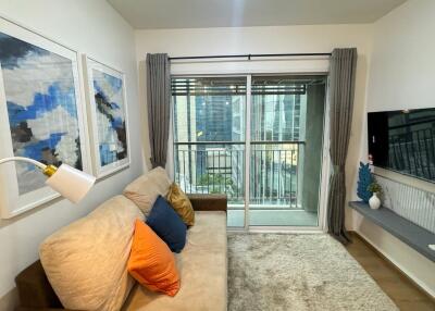 Cozy living room with a sofa, wall-mounted TV, and large window