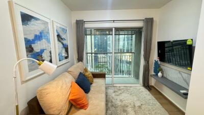 Cozy living room with a sofa, wall-mounted TV, and large window