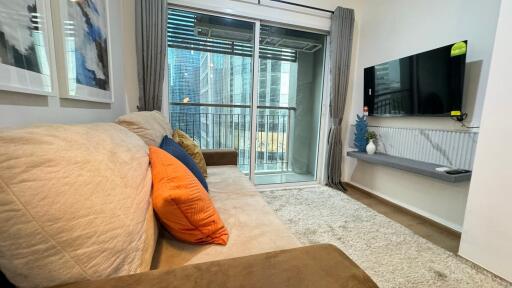 Modern living room with a couch, wall-mounted TV, and balcony access