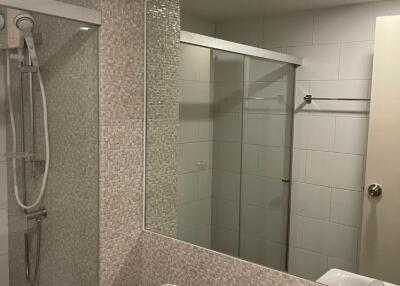 Modern bathroom with a shower, toilet, sink, and large mirror