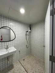 Bathroom with sink, shower, and white tile walls