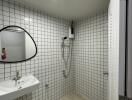 Bathroom with sink, shower, and white tile walls