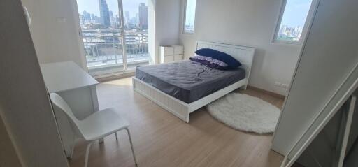 Bedroom with bed, desk, chair, and large windows with city view