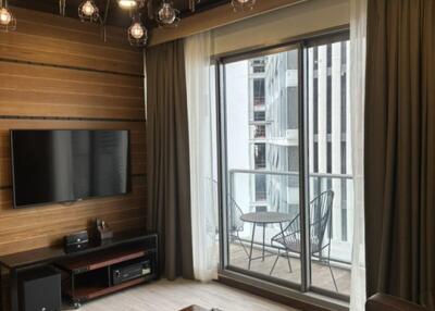 Modern living room with a wooden accent wall, TV setup, and a view of the balcony