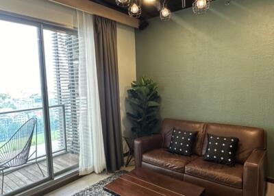 Cozy living room with leather sofa, coffee table, modern light fixture, and balcony view