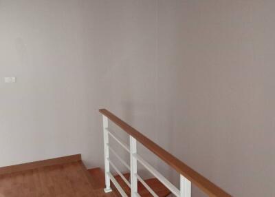 A minimalistic hallway with wooden floors and a handrail.