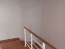 A minimalistic hallway with wooden floors and a handrail.