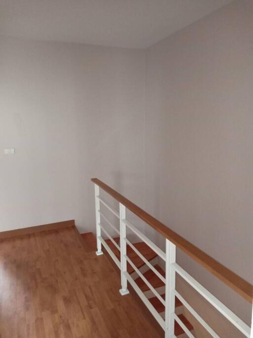 A minimalistic hallway with wooden floors and a handrail.