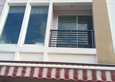 Front view of the building with a balcony and striped awning