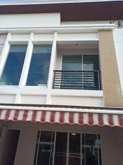 Front view of the building with a balcony and striped awning