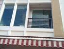 Front view of the building with a balcony and striped awning