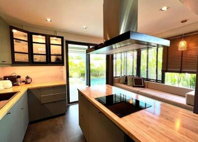 Modern kitchen with wooden countertops, glass cabinets, and seating area