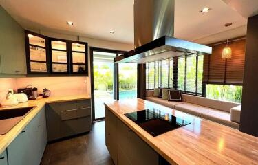 Modern kitchen with wooden countertops, glass cabinets, and seating area