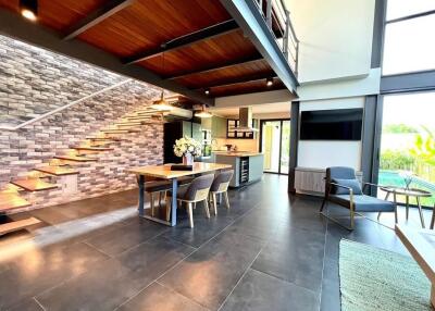 Contemporary open-plan living space featuring a dining area, modern kitchen, and large windows with a view of the garden.