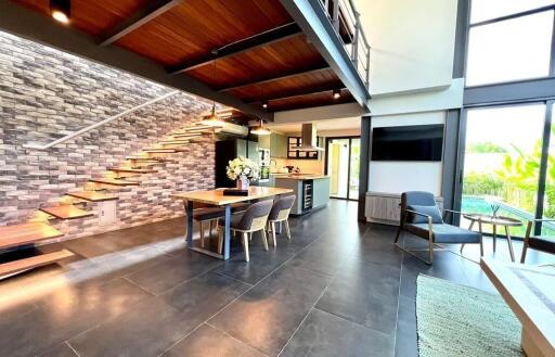 Contemporary open-plan living space featuring a dining area, modern kitchen, and large windows with a view of the garden.