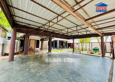 Covered outdoor area with concrete flooring and garden space.